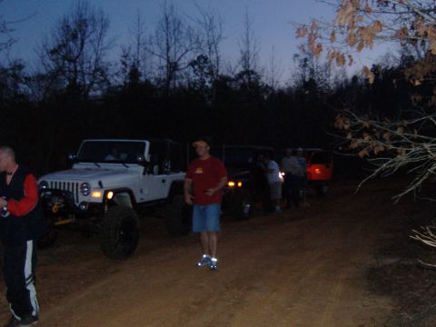 2004 Jeep Wrangler - A group of Jeeps, including a white Wrangler with a winch, are gathered off-road at dusk.