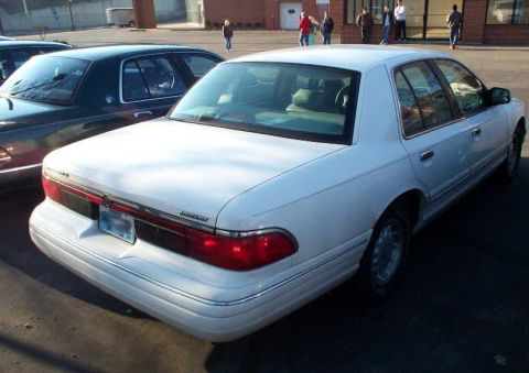 1998 Ford Crown Victoria - A white Mercury Grand Marquis is parked next to another car. The photo shows the rear of the Mercury.
