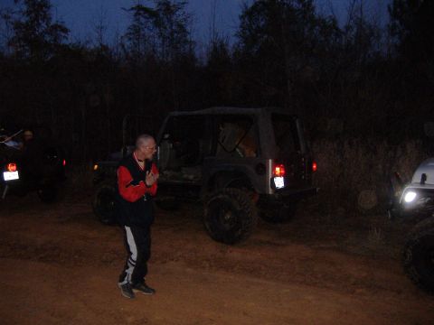 2004 Jeep Wrangler - Multiple Jeeps are parked on a dirt path at dusk, with a man standing in the foreground.