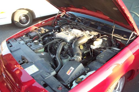 1998 Ford Crown Victoria - Engine bay of a 1998 Ford Crown Victoria, showing the K&N air filter and other components. Another vehicle is visible.
