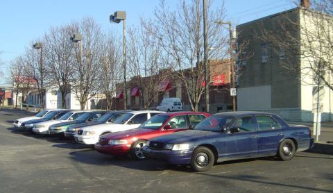 1998 Ford Crown Victoria - Several Ford Crown Victoria police cars are parked in a lot under a clear sky.