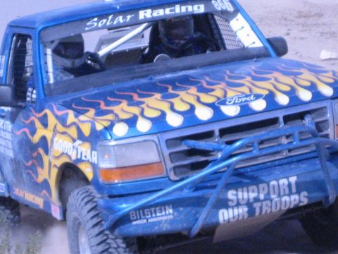 Blue Ford race truck with yellow flames and Goodyear decals close-up