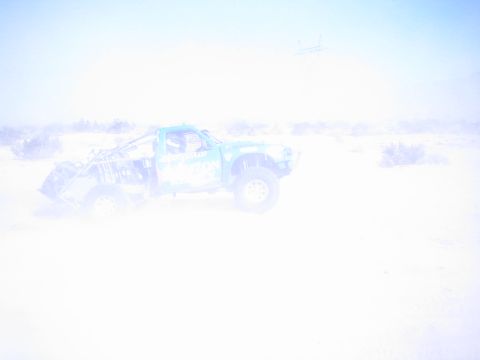 Washed-out overexposed photo of a faint blue truck in bright desert