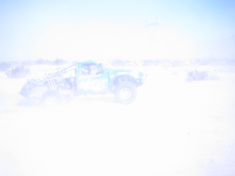 Washed-out overexposed photo of a faint blue truck in bright desert