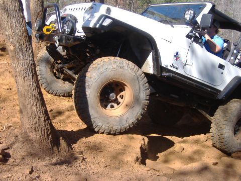 2004 Jeep Wrangler - White Jeep Wrangler TJ navigates a challenging off-road course with large tires and a lifted suspension.