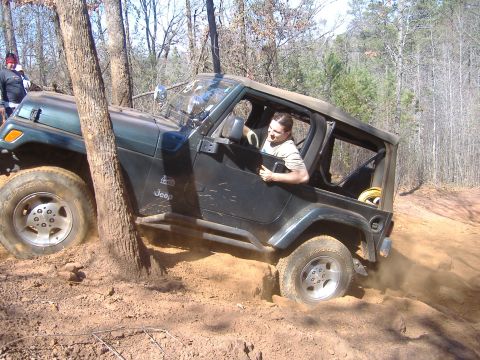 2004 Jeep Wrangler - 2004 Jeep TJ off-roading through a wooded area with muddy terrain.