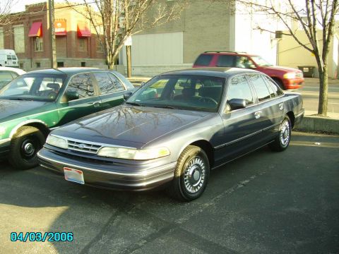 1998 Ford Crown Victoria - A 1998 Ford Crown Victoria sedan is parked in a lot next to another vehicle.