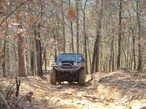 2004 Jeep Wrangler - A Jeep TJ navigates a rocky, wooded trail during the daytime.