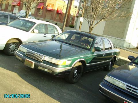 1998 Ford Crown Victoria - A green Mercury Grand Marquis is parked on a street next to other vehicles, with a date stamp of 04/03/2006.