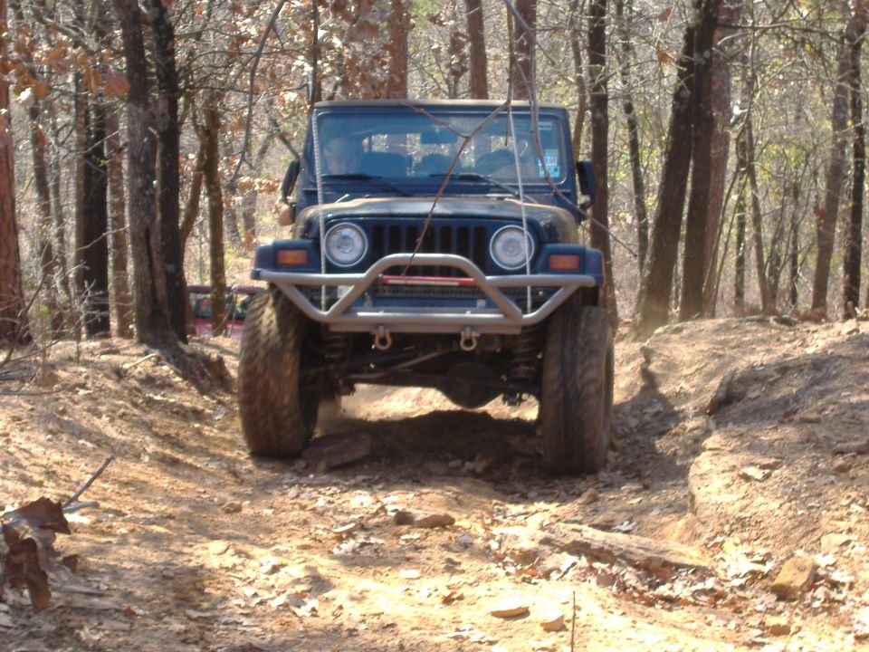Front view of a dark blue 2004 Jeep TJ navigating a rocky trail