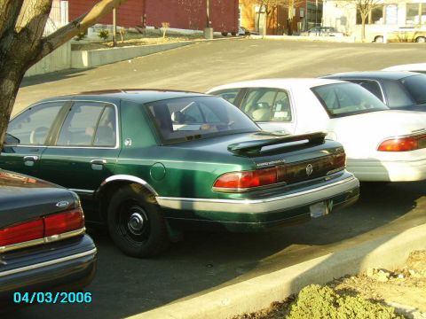 1998 Ford Crown Victoria - Rear view of a green Mercury Grand Marquis, parked alongside other vehicles on a sunny day.