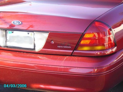 1998 Ford Crown Victoria - Rear view of a red 1998 Ford Crown Victoria, showing the taillights and a "Kenny Brown" emblem.