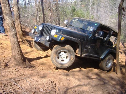 2004 Jeep Wrangler - A Jeep TJ navigates a challenging off-road trail, demonstrating its climbing capability on uneven terrain.
