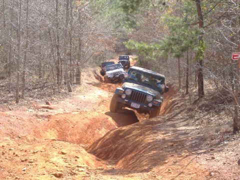 2004 Jeep Wrangler - Multiple Jeeps navigate a challenging off-road trail with steep inclines and turns.