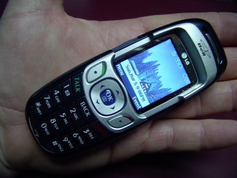 1990 Lincoln Town Car - LG flip phone with "Bell" logo held in a hand. Screen shows date and time.