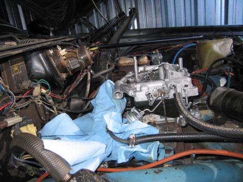 1991 Ford LTD Crown Victoria - carburetor sits atop the intake in an engine compartment, framed by hoses, wiring and a blue shop towel.