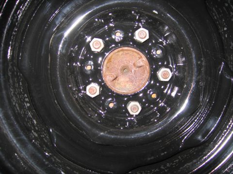 1991 Ford LTD Crown Victoria - detailed view of a black steel wheel's hub, showing surface rust ringed by chrome lug nuts.