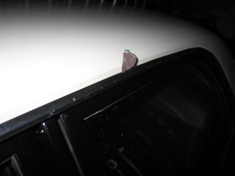 1991 Ford LTD Crown Victoria - nighttime close-up of a white car body panel meeting a dark windshield, with a small object resting on the cowl.