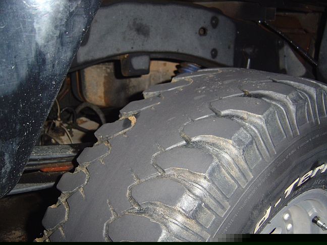 Close-up of a worn tire and suspension parts on a vehicle