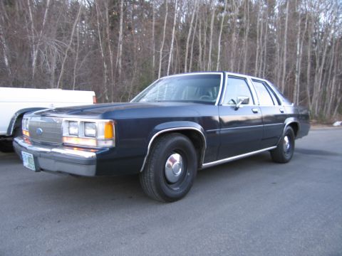 1991 Ford LTD Crown Victoria - Dark blue sedan parked on asphalt with trees in the background.
