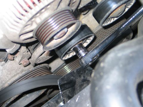 1994 Ford Bronco - Tight close-up inside an engine bay of the serpentine belt drive, showing the grooved alternator pulley, a smooth idler pulley and the spri…