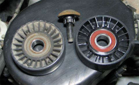 1994 Ford Bronco - A side-by-side comparison of two accessory-belt idler pulleys with a mounting bolt between them, an old, rust-stained pulley on the left an…