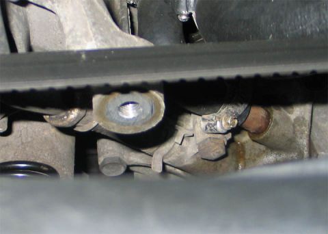 1994 Ford Bronco - Tight engine-bay shot of a bare idler pulley mounting boss on an aluminum accessory bracket with the pulley removed, exposing the threaded…