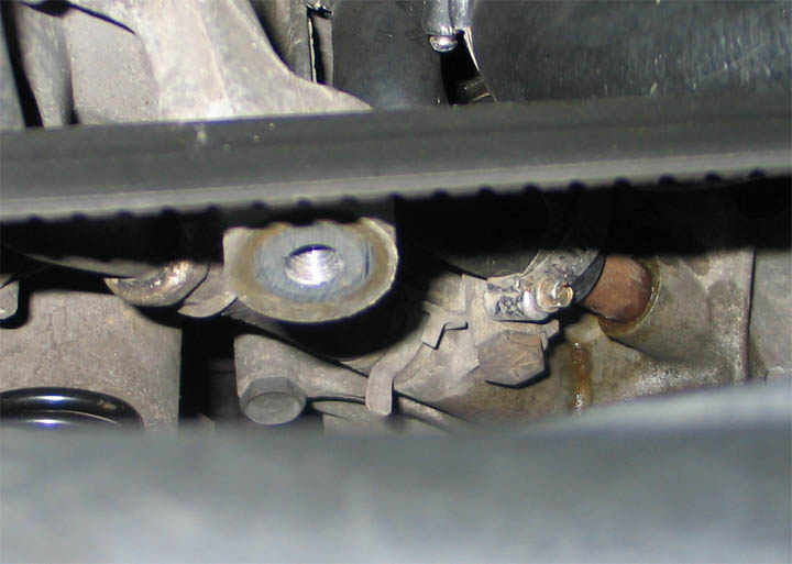 Bare idler pulley mounting boss on an engine bracket with pulley removed