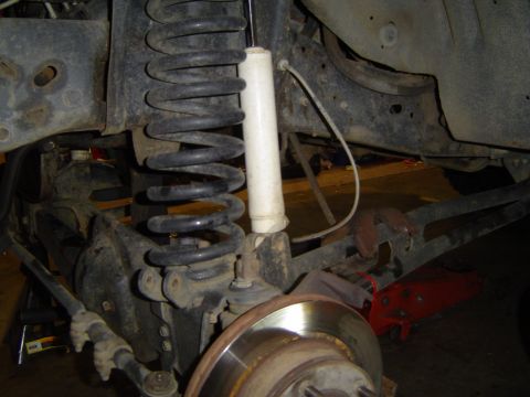 1989 Ford Bronco - Close-up view of the front suspension system, showing the coil spring, shock absorber, and brake rotor.