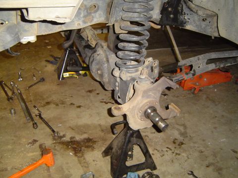 1989 Ford Bronco - Front axle and suspension parts of a vehicle are disassembled and supported by jack stands.