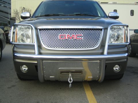 1990 Ford Bronco - Front view of a gray GMC SUV fitted with a chrome brush guard and front winch, parked in a lot.