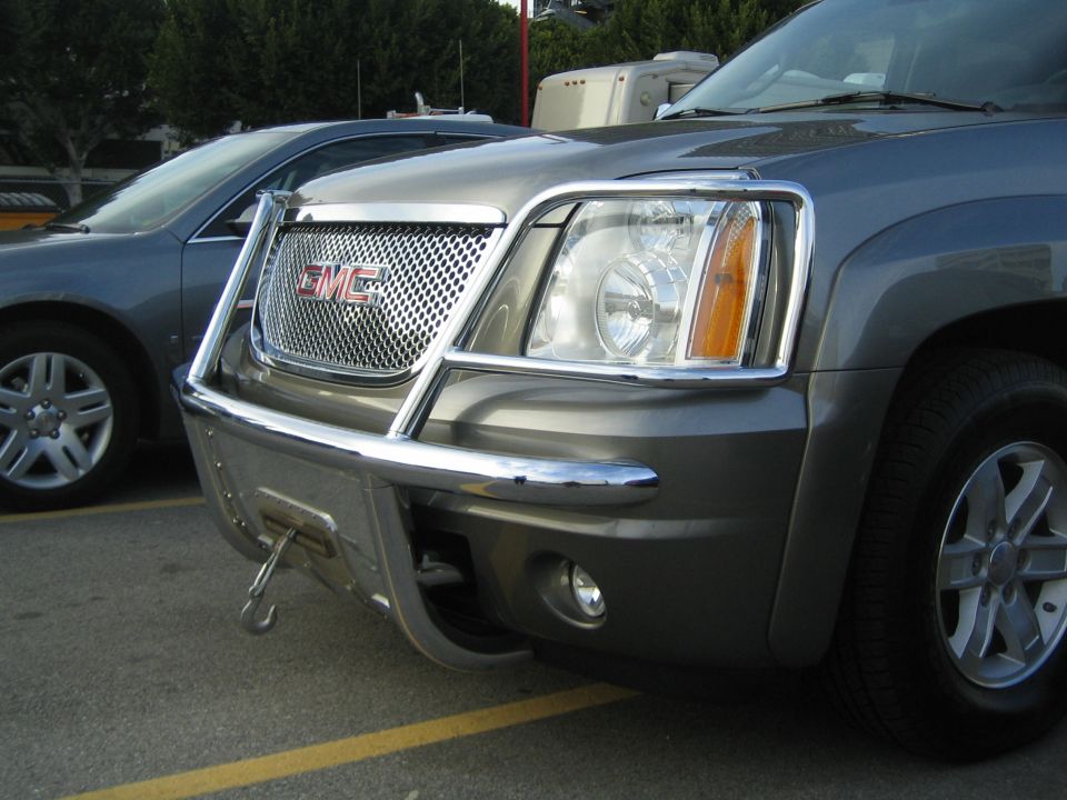 Front corner of gray GMC SUV with chrome grille guard in parking lot