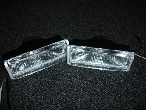 1993 Ford Taurus - Pair of aftermarket fog lights shown on a dark textured surface.