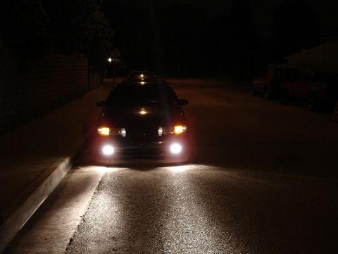 1993 Ford Taurus - A 1993 Ford Taurus sedan is parked on a street at night, its headlights illuminating the road ahead.