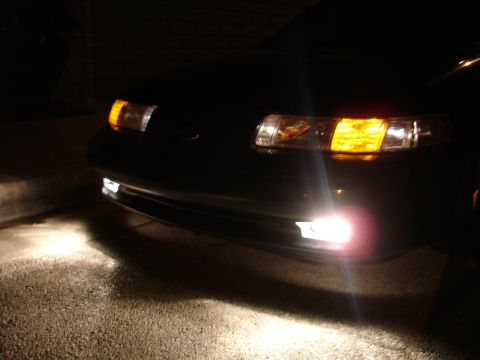 1993 Ford Taurus - Front view of a 1993 Ford Taurus showing illuminated fog lights and headlights.