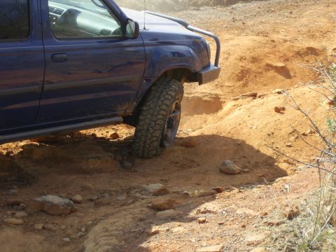 1996 Ford Bronco - A blue SUV tackles a challenging off-road course on a sunny day.