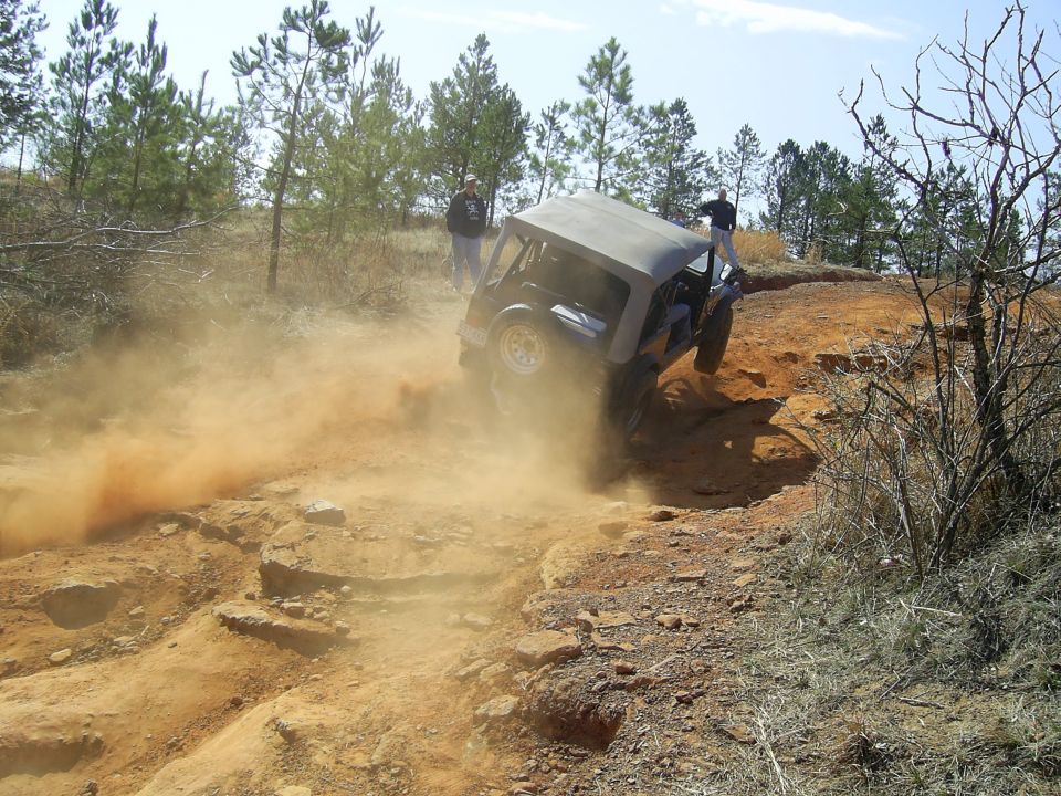 Off-road vehicle kicking up dust on a rocky trail