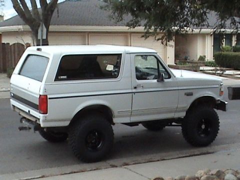 1994 Ford Bronco - Side view of a lifted white Ford Bronco with aftermarket wheels and tires.