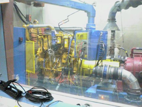1986 Ford Bronco - A large industrial engine is connected to various hoses and electrical wires on a test stand.