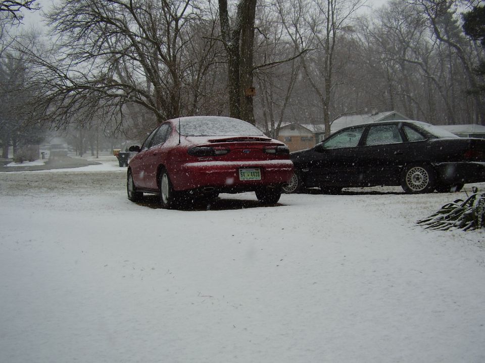 1997 Ford Taurus rear view in snow, parked next to a black sedan