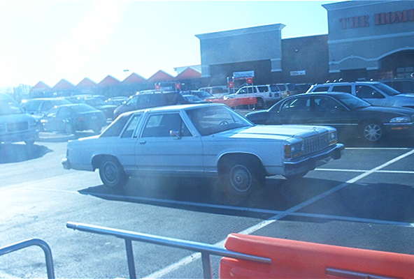 1985 Ford Crown Victoria LTD parked in a lot with other vehicles and a store in the background