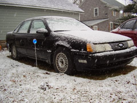 1997 Ford Taurus - A black sedan sits in the snow, with a red car partially visible to the right.