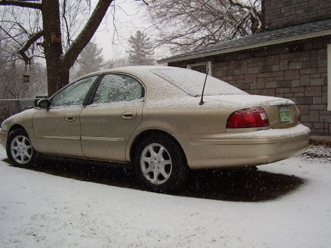 1997 Ford Taurus - A gold sedan sits in the snow, its body style suggesting a model year around 2000.