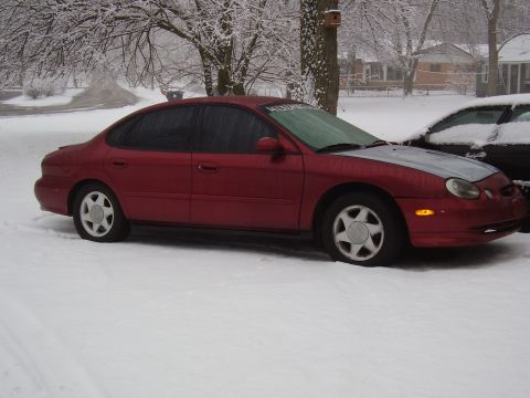 1997 Ford Taurus - Red 1997 Ford Taurus sits in the snow with a second vehicle behind it.