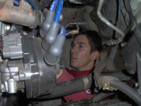 1996 Ford Probe - Mechanic working on engine parts, focusing on spark plug wires and distributor assembly.