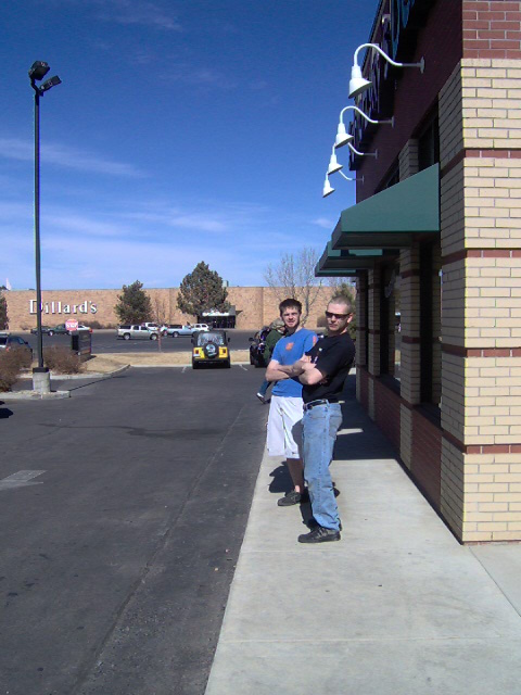 1996 Ford Probe - Two men stand on a sidewalk outside a brick building, with a yellow Jeep and other vehicles in the background.