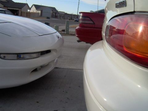 1996 Ford Probe - Two cars parked close together, one white and one red, with a focus on the front of the white car and the rear of the red car.