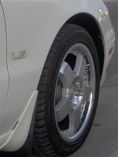 1996 Ford Probe - Close-up of a white car's fender, showing an 'LS' badge and a multi-spoke alloy wheel.