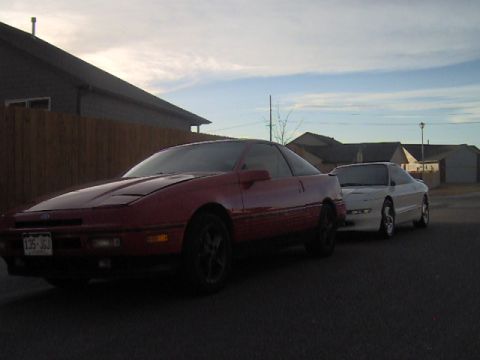 1996 Ford Probe - Two Ford Probe cars are parked on a street with houses in the background.