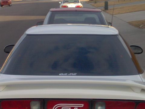 1996 Ford Probe - A white coupe with a spoiler is parked behind another vehicle on a street.